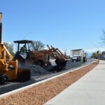 Heavy machinery lays new asphalt on a roadway reconstruction project.