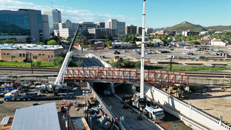 White construction cranes lift a metal bridge into place at the Stone Avenue underpass in Downtown Tucson.