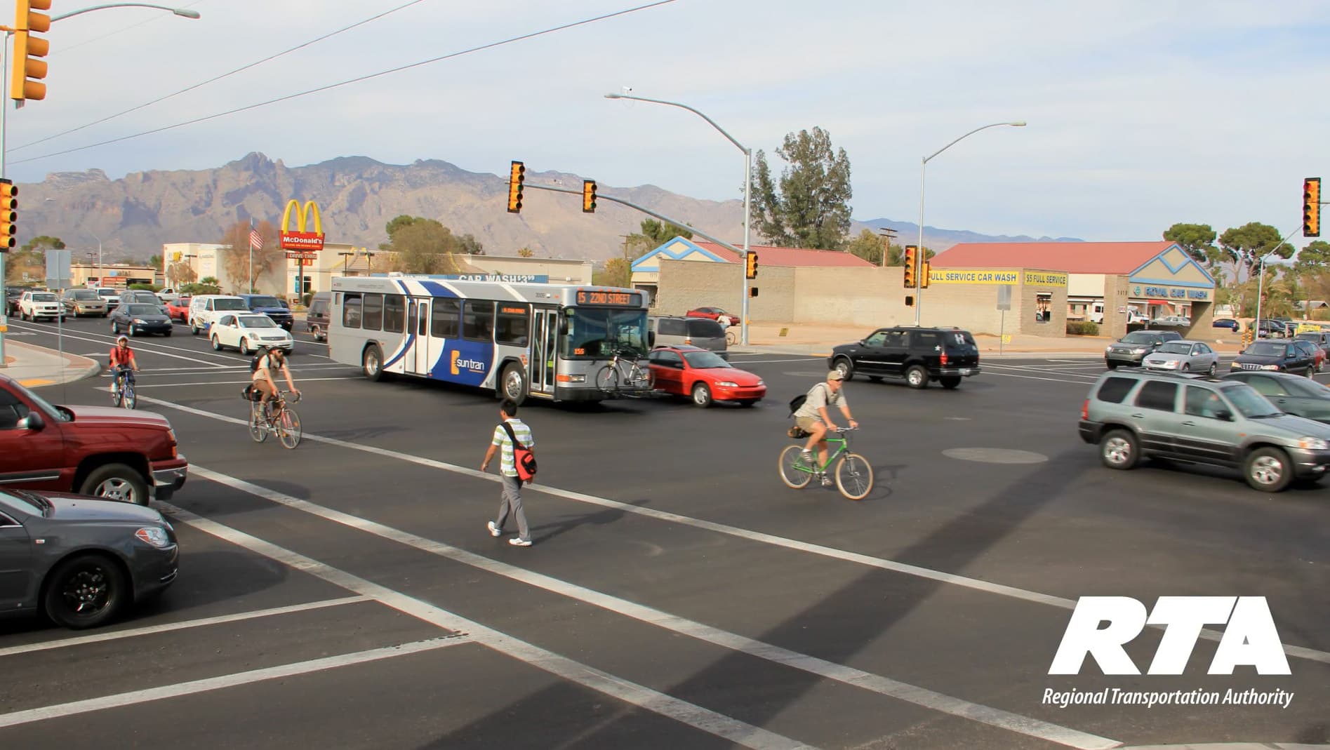 Tucson intersection with vehicles, a bicycle rider, and a pedestrian.